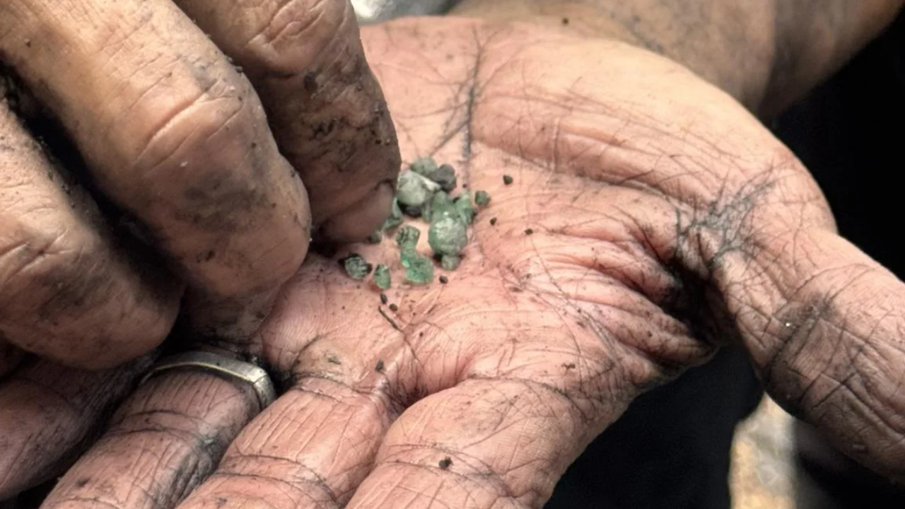 Hand holding raw emerald crystals